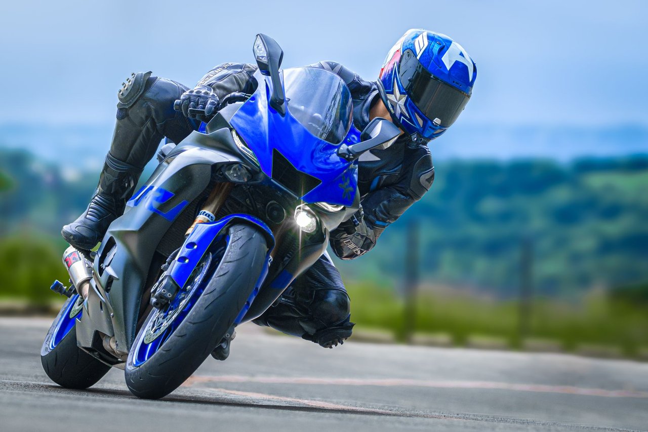 Motociclista usando equipamento de proteção faz uma curva acentuada com uma motocicleta esportiva em uma pista.