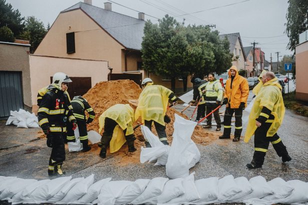 Equipe de emergência coloca sacos de areia em uma rua molhada para conter possíveis alagamentos.