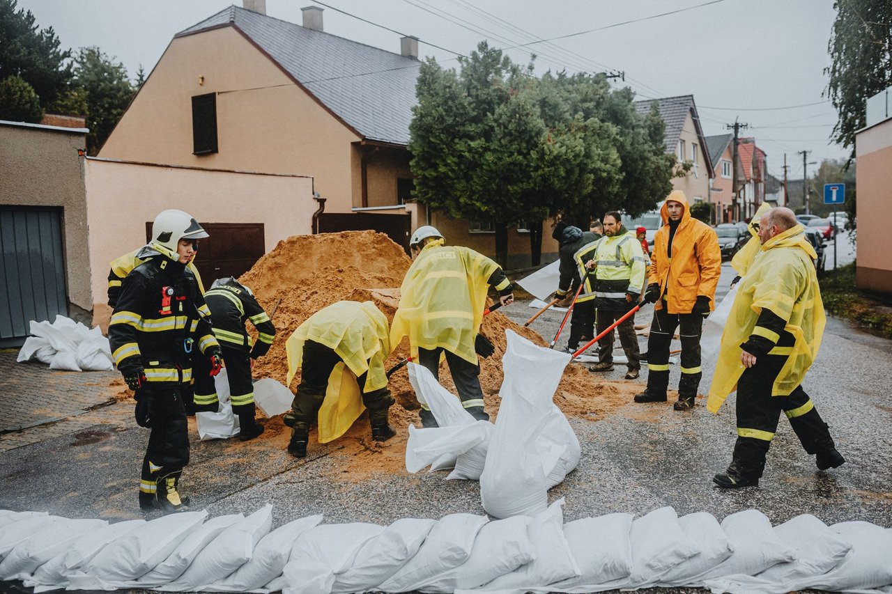 Equipe de emergência coloca sacos de areia em uma rua molhada para conter possíveis alagamentos.