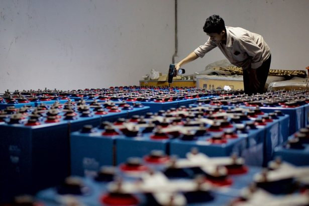 Trabalhador inspeciona conjuntos de baterias industriais em uma instalação de armazenamento de energia.