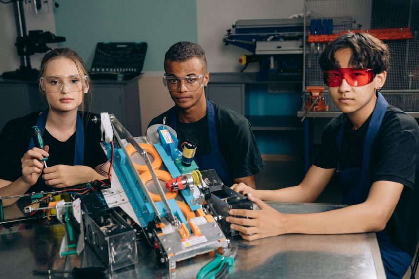 Adolescentes trabalham em equipe em um projeto de robótica dentro de um laboratório técnico.