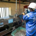 Trabalhador de fábrica opera uma mesa vibratória para o processamento de minério.