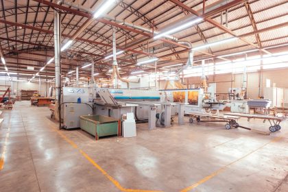 Interior organizado de uma fábrica brasileira, com máquinas industriais e área de produção.