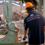 Trabalhadores usando equipamentos de proteção operam máquinas em uma fábrica.