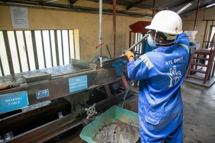 Trabalhador de fábrica opera uma mesa vibratória para o processamento de minério.